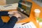 Close up of business person`s hands uses laptop keyboard works in the office with cup of coffee on the wooden table. Business and