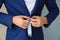 Close-up business stylish man buttoning his blue jacket, standing in a stylish office with designer repair.