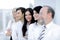 Close-up of a business woman in selective focus looking at a camera with her colleagues in formal wear standing behind