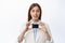 Close up of business woman in suit shows plastic credit card, recommends banking service, white background