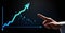 Close up of businessman hand pointing at growing graph on dark background. Business growth concept