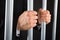 Close-up of businessman holding bars in jail