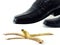 close-up businessman leather shoes about to step on banana peel isolated on white background