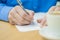 Close-up businessman sitting at the table in office interior and attentively writing some notes. Coffee on the table