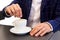 Close up businessman stirring hot coffee at cafe