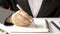 Close-up of a businesswoman using a pen to write a wooden desktop notebook.