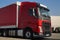 Close-up of the cabin of a red truck. Trucks parked in the background