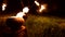 Close-up. Camera follows man in the dark with a burning ball, poi. Fire show