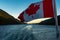 A close up of the Canadian flag flying in the wind at the back of ferry as the boat makes it way through the Inside