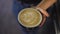 Close-up cappuccino coffee cup with leaf form drawn with milk top view. Tasty morning hot drink in female Caucasian hand