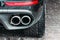 Close up of a car dual exhaust pipe parking lights, brake lights and wheel tires.