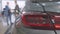 Close-up of car headlight with blurred men shaking hands at background. Blurred Caucasian client and dealer making