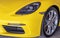 Close-up of Car Headlights and Car Wheel of Yellow Porsche Sports Car parked in the parking lot