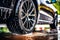 A close-up of a car tire being carefully cleaned and dressed by a detailer, showcasing the attention given to every aspect of the