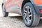 Close up of car tyres. Back view of a parked car over a road covered with autumn leaves.