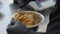 Close-up of caramel and nuts mixing in bowl. Slim young female hands in black gloves preparing cake layer in commercial