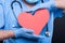 Close-up of cardiologist wearing scrubs holding red heart shape