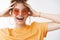 Close-up carefree excited good-looking smiling young redhead freckled girl wearing orange t-shirt sunglasses touching