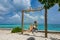 CLOSE UP: Carefree woman in a bikini swings on a swing on an exotic beach