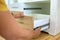 Close up of carpenter hands installing wooden drawer on sliding skids in contemporary cupboard cabinet