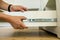 Close up of carpenter hands installing wooden drawer on sliding skids in contemporary cupboard cabinet