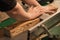 Close-up of carpenter, joiner worker hands pressing, pushing down, setting wood board on cutting machine in the workshop