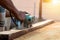 Close-up of a carpenter `s hand using a planer on a wooden floor and creating dust from work