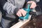 Close-up of a carpenter`s hand working with an electric plane with suction of sawdust. Leveling and sanding wooden bars