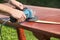 Close-up of carpenter`s hands working with electric sander - polishing old color from wooden table