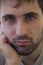 Close-up of caucasian boy with beard and clear eyes. Sad, severe, hard expression.