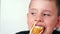 Close-up Caucasian cute boy 6-8 years old with appetite feeling hungry eats fresh sushi using chopsticks .Child puts whole sushi i