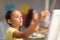 Close-up of caucasian elementary schoolgirl painting on easel in drawing class