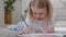 Close-up Caucasian little child daughter preschool girl concentrated toddler blonde draws picture with colored pencils