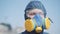 Close-up of Caucasian man in protective chemical suit and respirator. Portrait of worker standing outdoors on sunny day