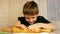 Close-up caucasian preschooler boy helps to cook in the kitchen rolls out the dough with a rolling pin. The child makes the dough