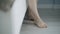 Close-up, caucasian woman lowers her bare feet from bed to laminate floor