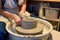 close up of ceramist woman hands working and shaping clay on the lathe or potter\'s wheel inside a pottery workshop