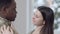 Close-up of charming loving Caucasian woman and affectionate African American man in military uniform dancing at home