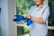 Close-up charming young woman housewife putting on blue rubber work gloves to clean the house