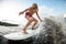 Close-up of cheerful athletic young man on board riding wave