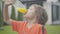 Close-up of cheerful Caucasian boy drinking healthful juice outdoors. Portrait of happy kid enjoying refreshing drink at