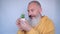 Close up of cheerful mature man with small potted plants. Senior man laughing on grey background