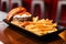 Close up Cheeseburger with grilled beef, feta cheese and sliced tomato served with fries in black plate