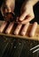 Close-up of a chef hands adding dry spices to sausages before cooking. Grilling concept with Munich sausages