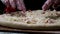 Close up for chef hands in transparent gloves touching unbaked pizza on black background, cooking concept. Frame. Man in
