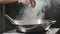 Close-up of chef pours seasonings in fried food in wok pan, slow motion.