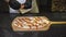 Close-up of chef prepares delicious Italian pizza in restaurant. Frame. Chef puts slices of ham and sausage on baked