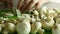 Close-up of the chef`s hand cuts edible champignons with a knife on a cutting board. A lot of champignons are cooking in the kitch