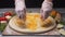 Close-up of chef`s hands covering the pizza dough with cheddar on a wooden board before the other ingredients. Frame