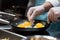 close-up of chef& x27;s hands frying eggs in a skillet